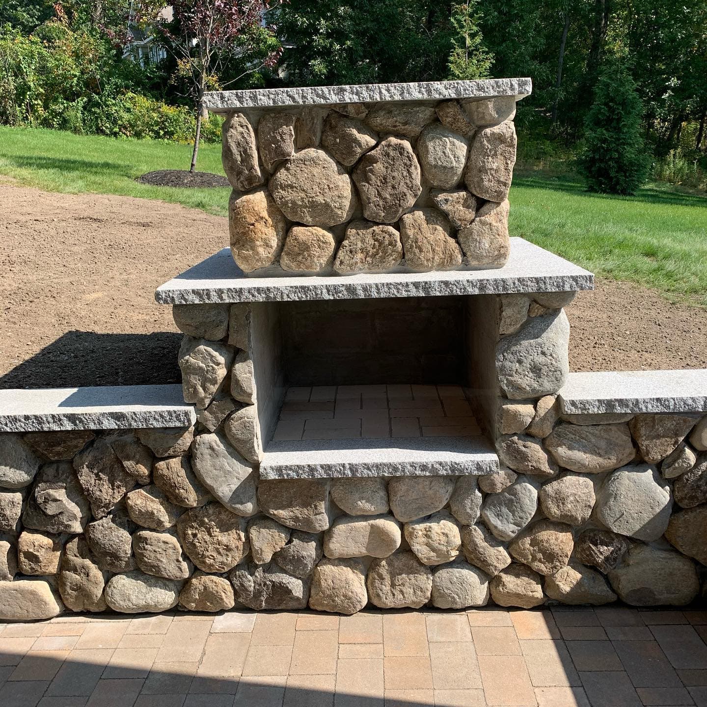 Fieldstone outdoor fireplace with granite mantel