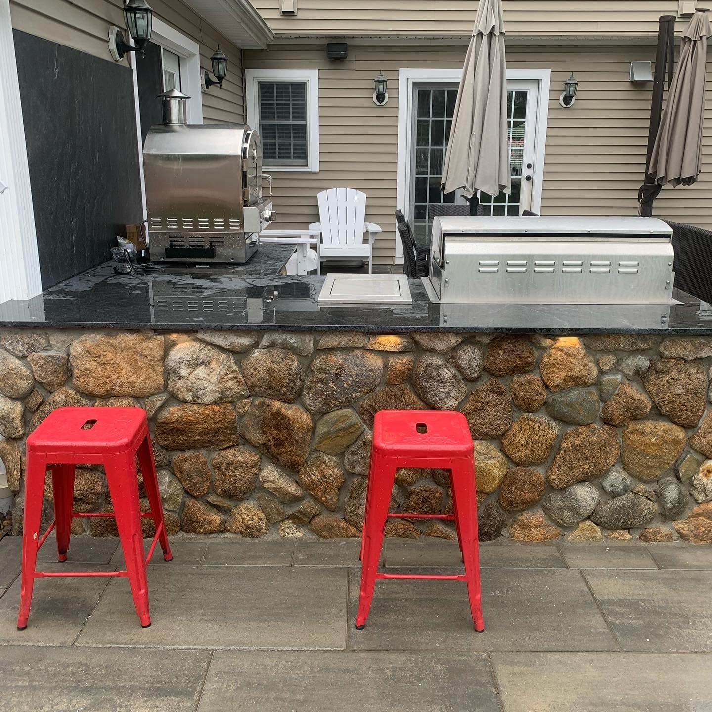 Fieldstone outdoor bar with a granite top and two red stools