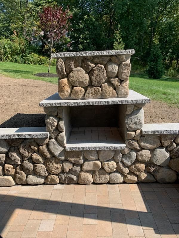Fieldstone outdoor fireplace with granite mantel and hearth