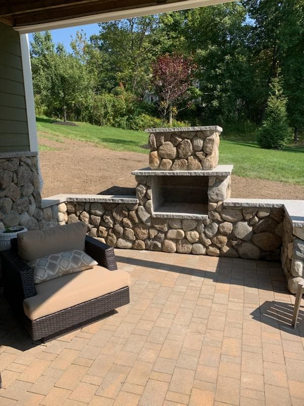 Fieldstone seat wall and fireplace around a paver patio