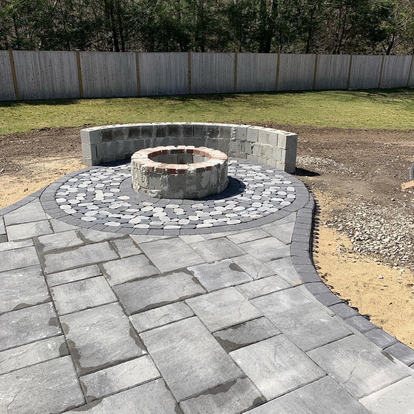 Paver patio with circular fire pit and fieldstone seat wall