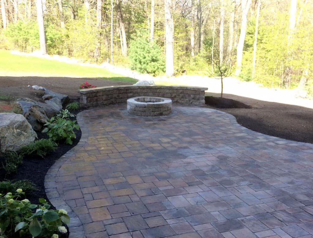 Curved paver patio with fire pit, seat wall and plantings in Middleton