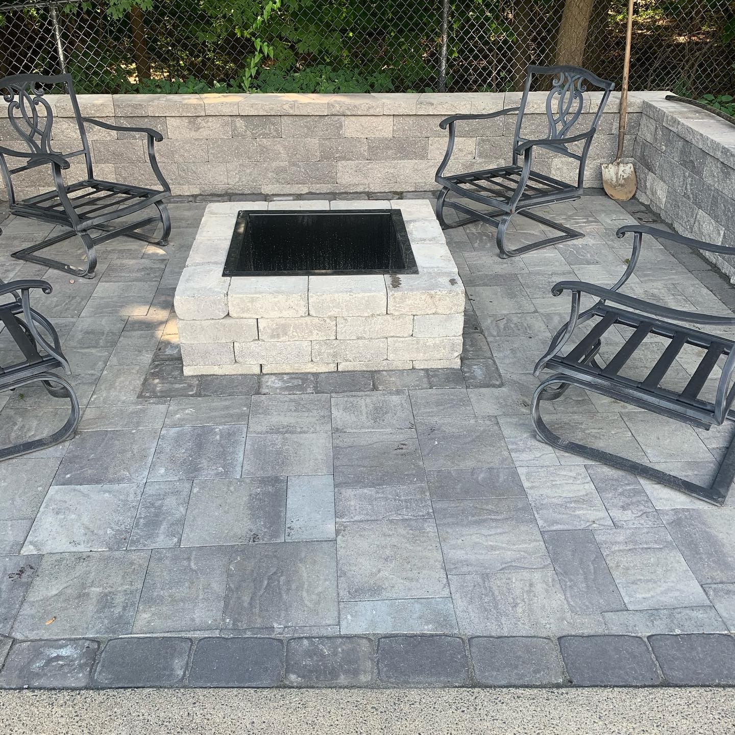 Square block fire pit on a paver patio with a seat wall