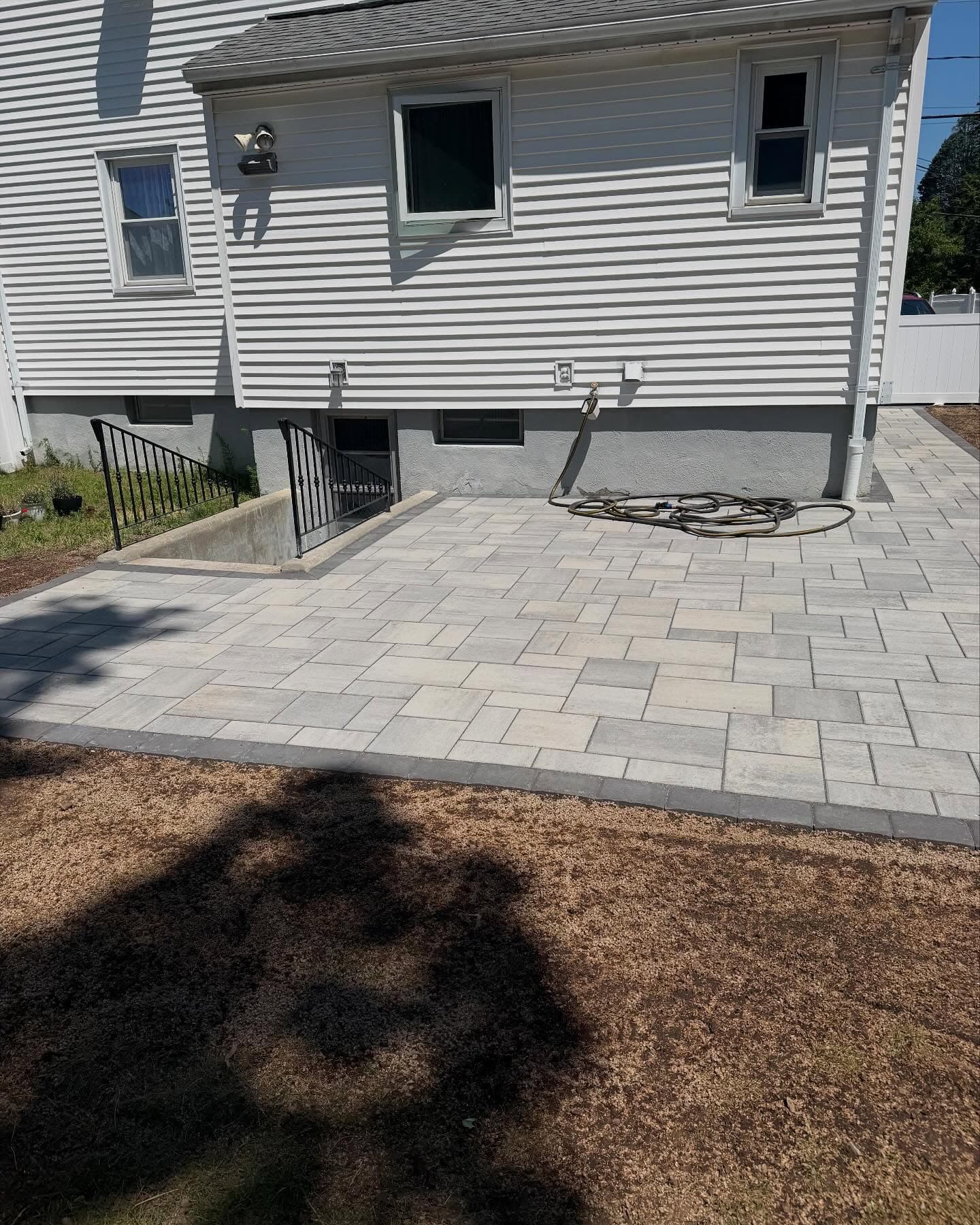 Simple rectangular paver patio off the back of a house