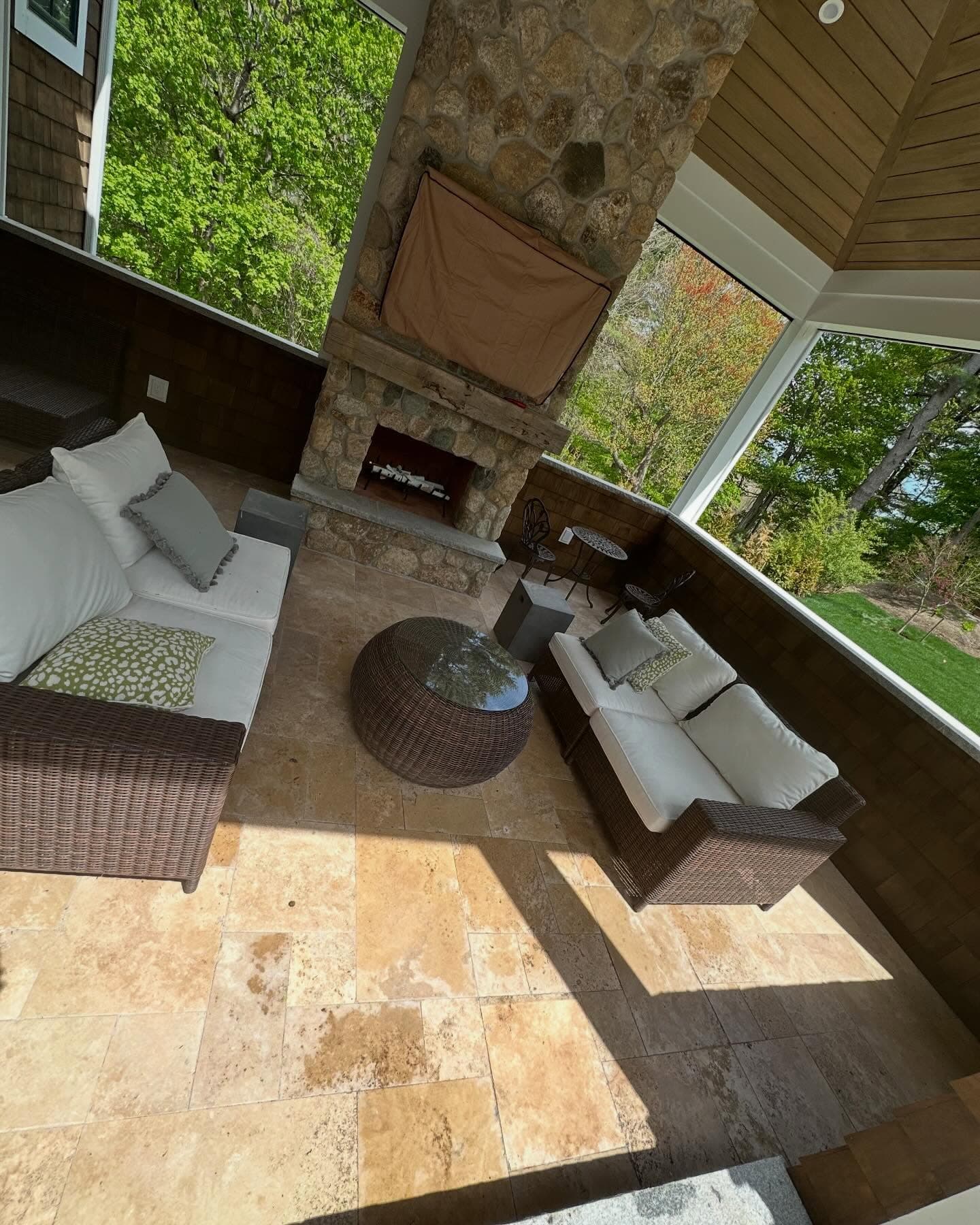 Travertine floor on a covered porch with a fieldstone fireplace