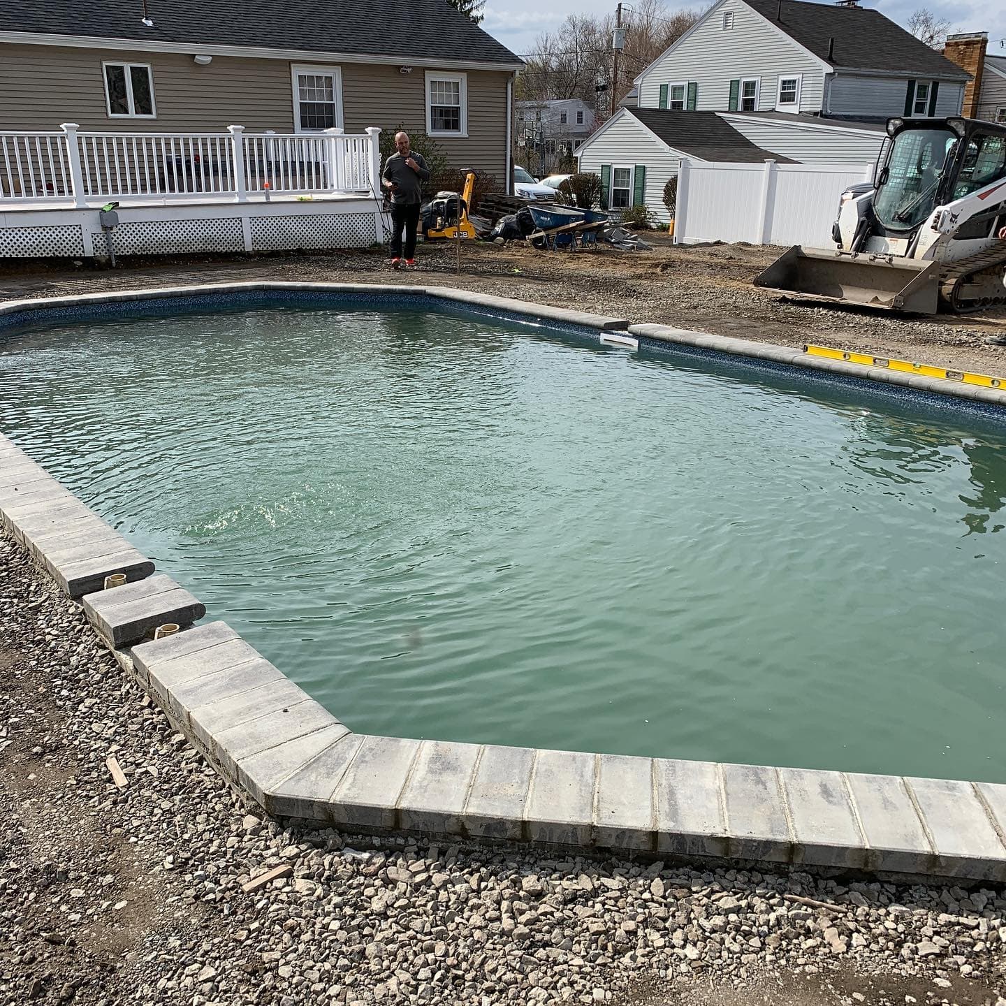 Pool edge with new coping going in and a skid steer working in the background