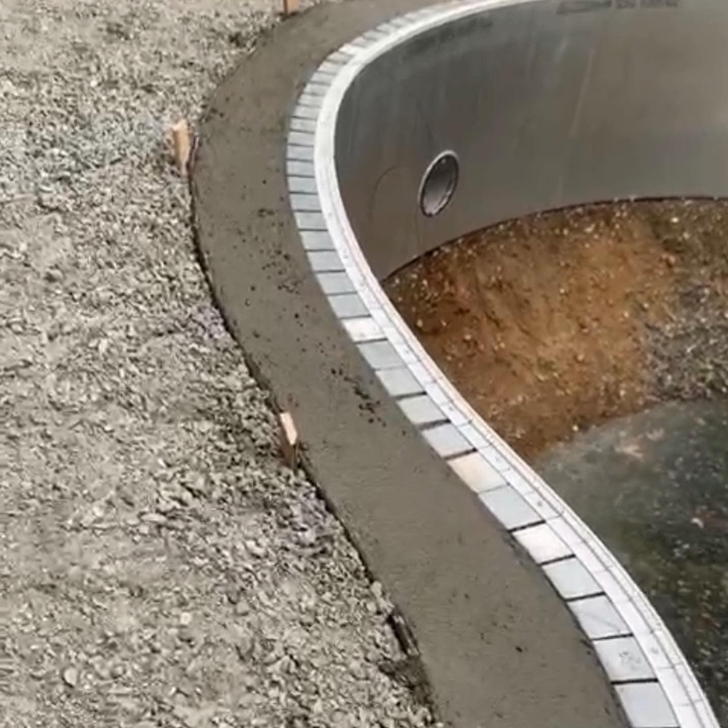 Close-up of bullnose paver coping being set along a curved pool edge