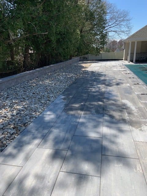 Large-format paver walkway along the side of a pool
