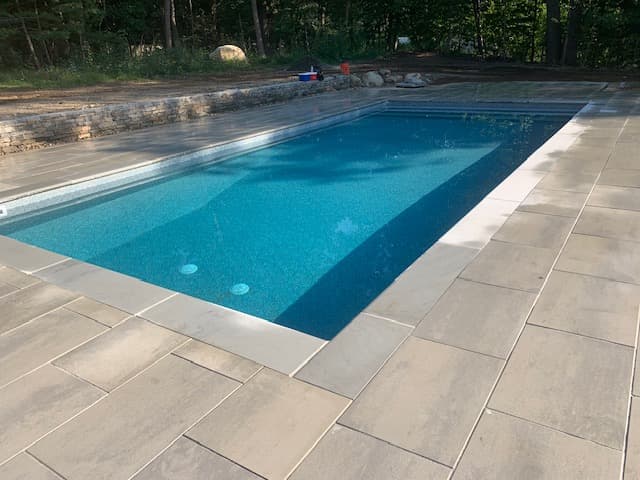 Rectangular pool with light paver slabs and coping