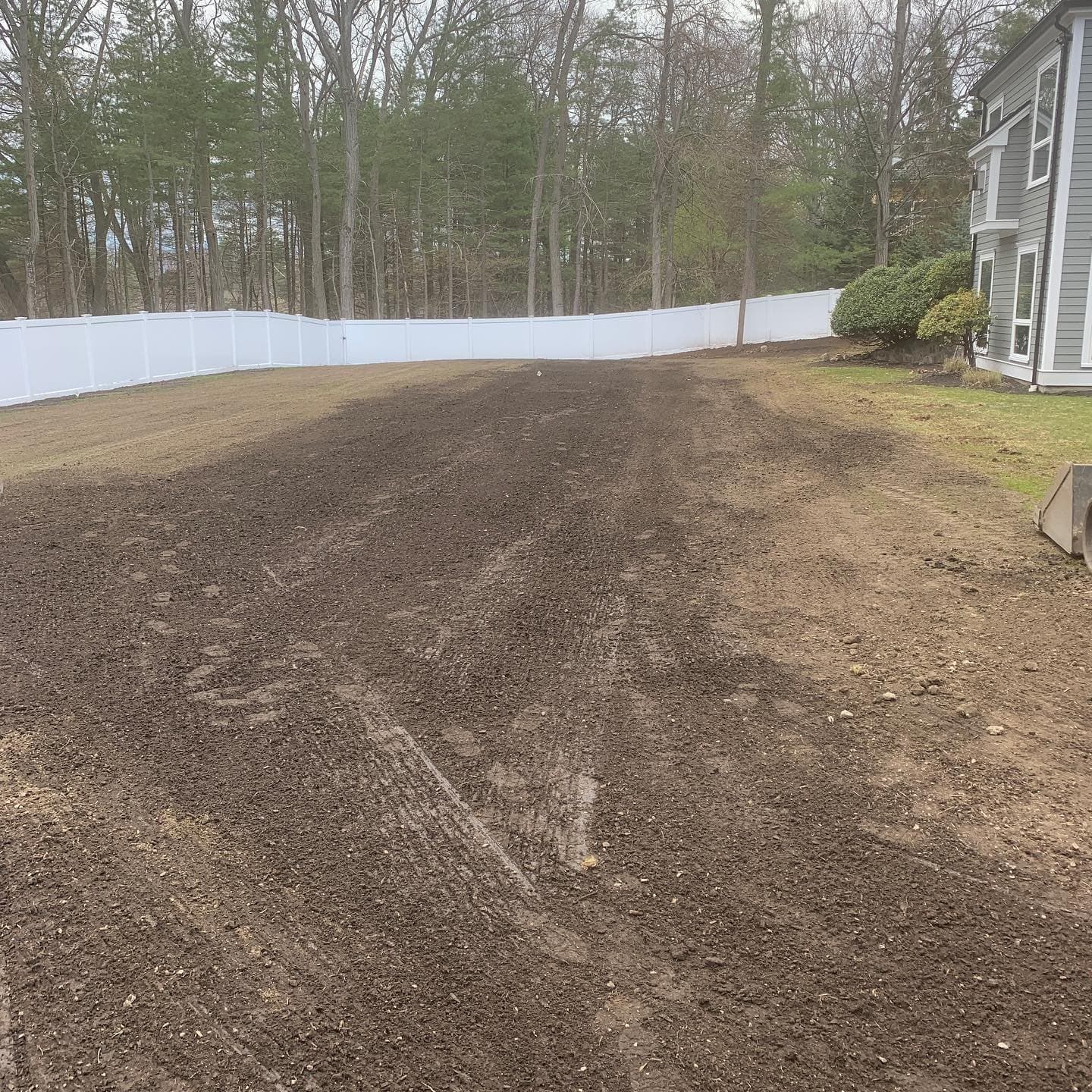 Graded yard along a white fence