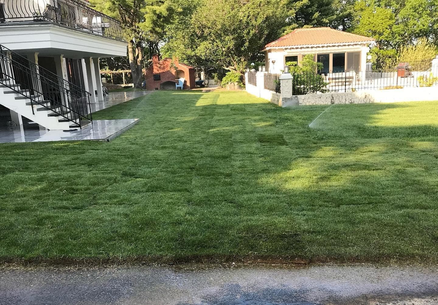Freshly laid lawn stretching to a pool house
