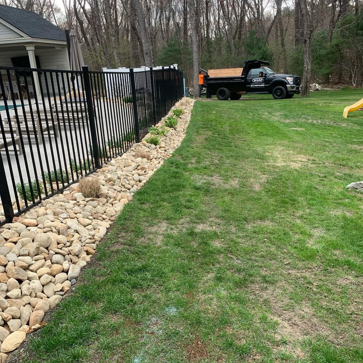 New lawn with a river rock border along a fence