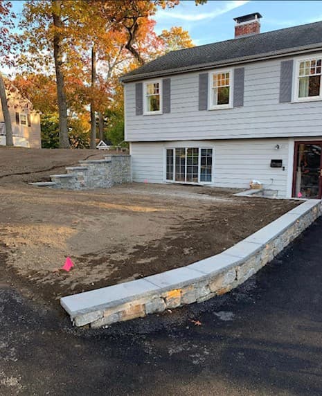 Stone-faced retaining wall with bluestone caps and steps on a Lynnfield lot