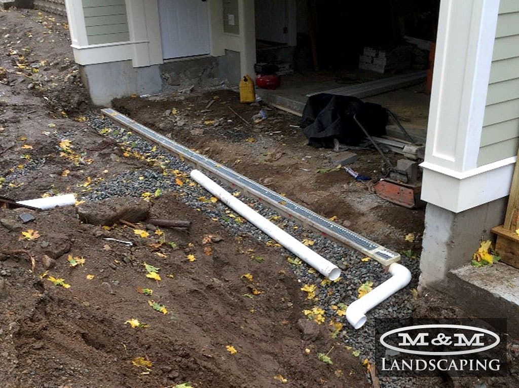 White drain pipe connected to a downspout running away from a house