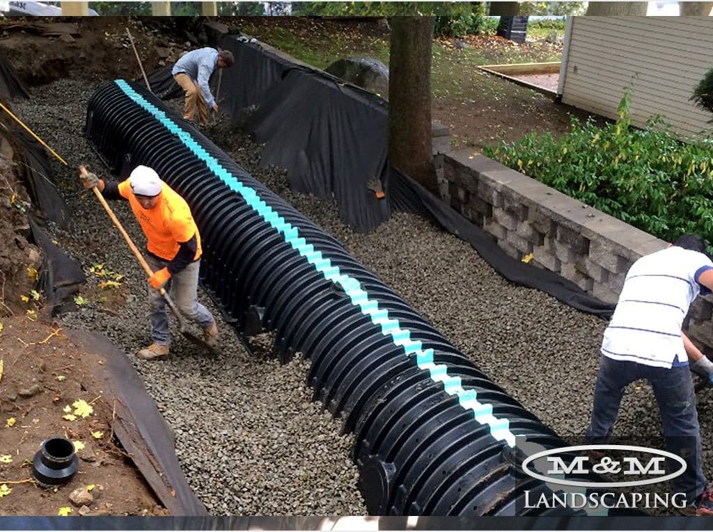 Crew setting perforated drainage chambers in a lined trench