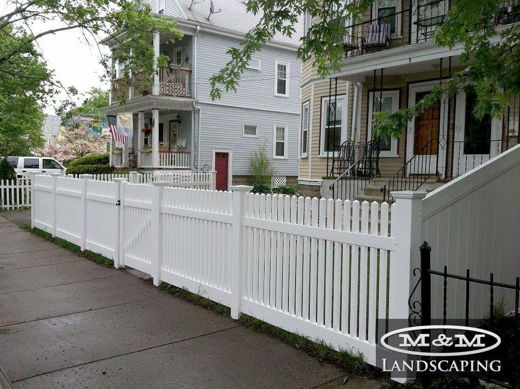 White vinyl picket fence along a city sidewalk