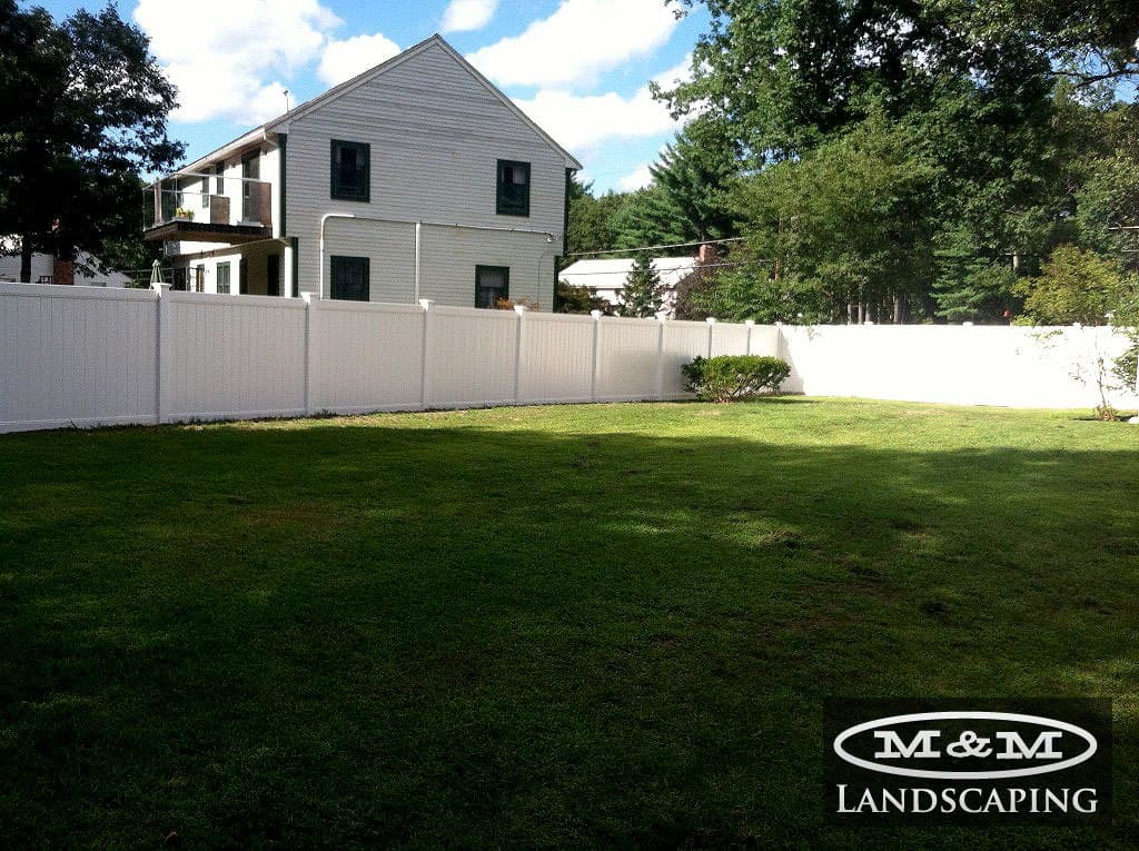 White vinyl fence enclosing a backyard lawn