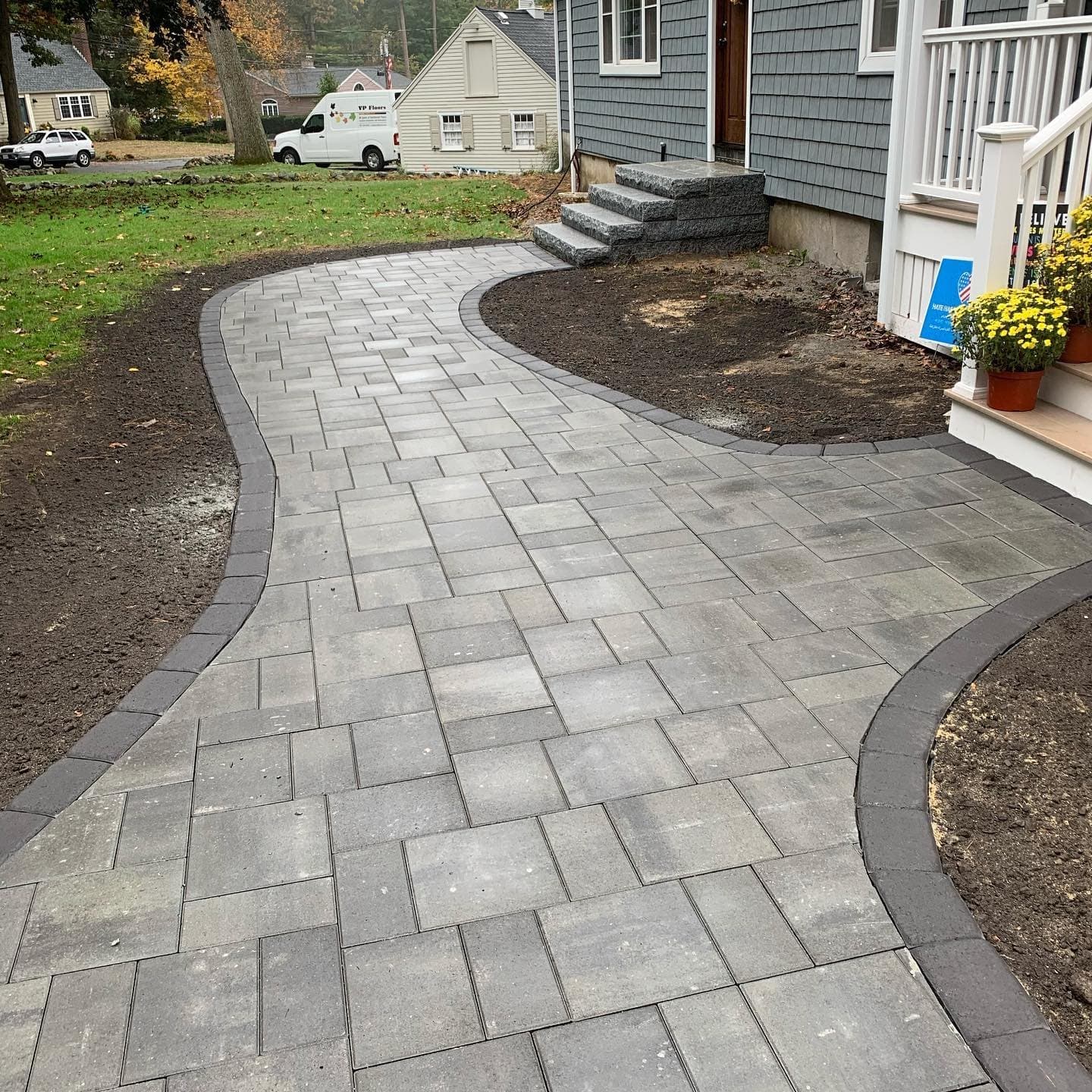 Curved gray paver walkway with a charcoal border leading to a front porch