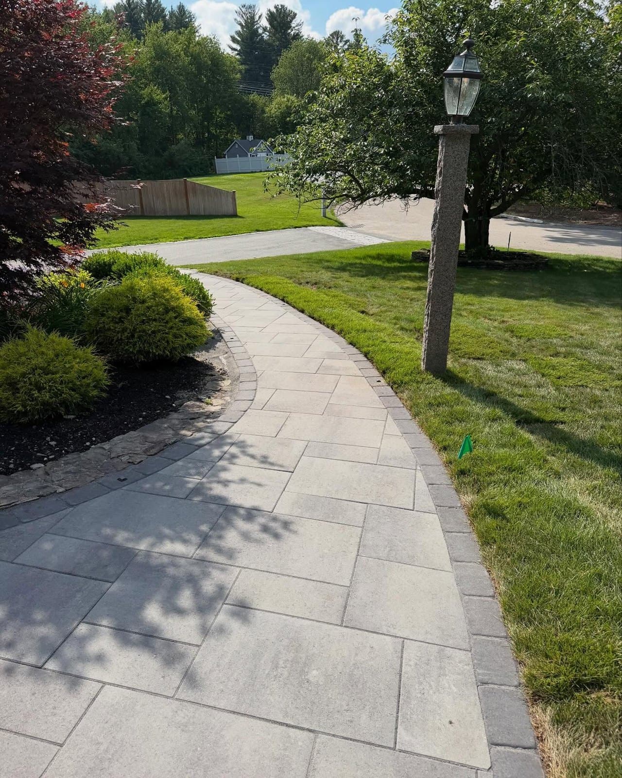 Curved paver path through a front lawn past a lamp post