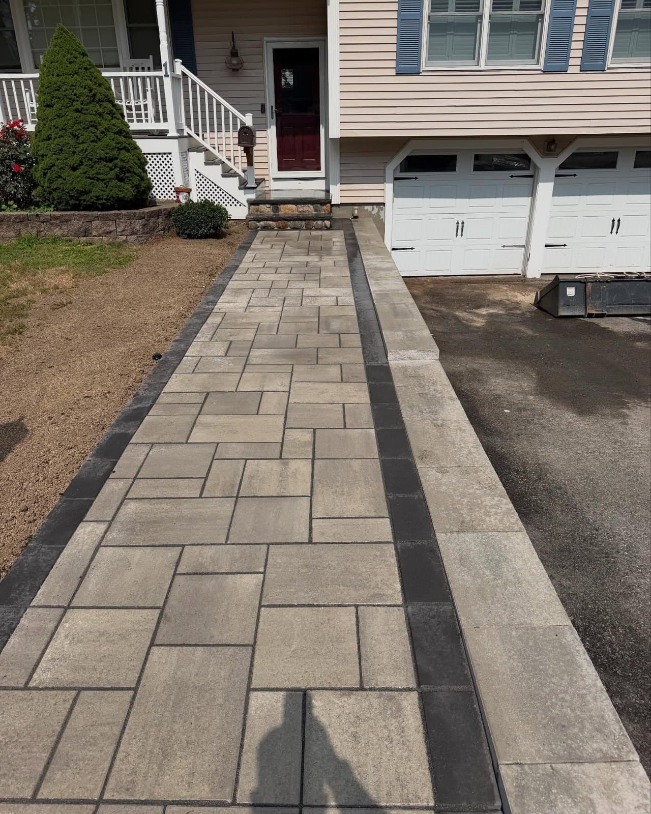 Straight paver walkway with a dark border running to a garage