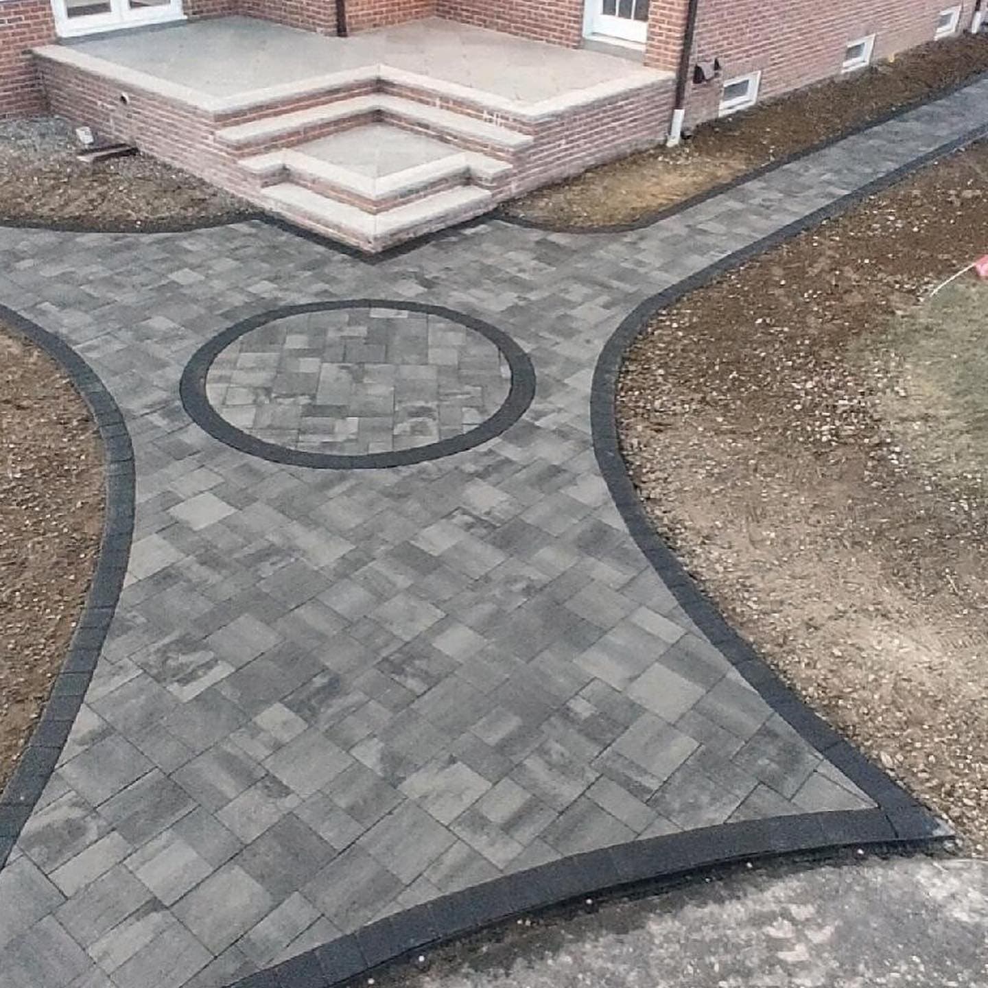 Paver walkway with a circular inlay and a charcoal border