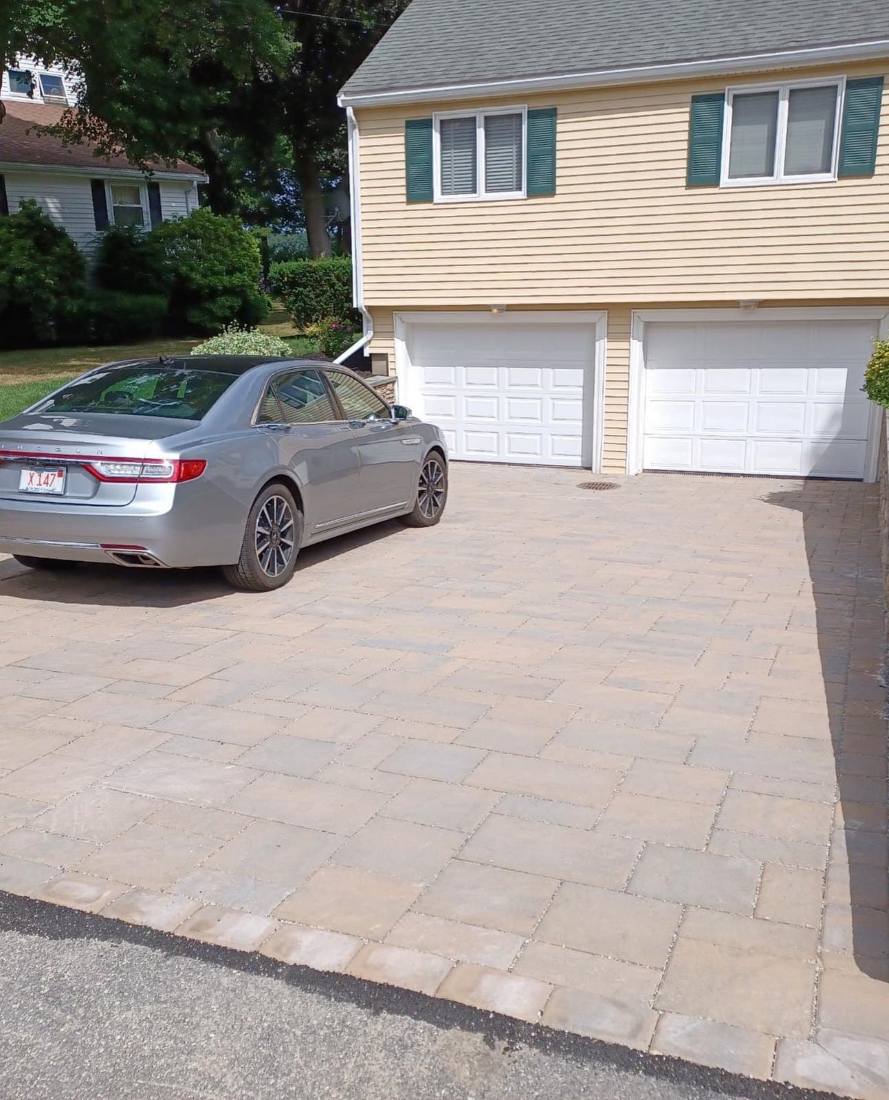 Tan paver driveway in front of a two-car garage