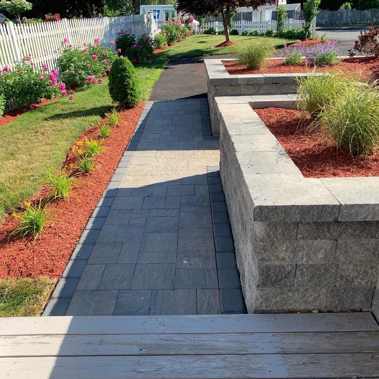 Block raised planting beds beside a charcoal paver walkway