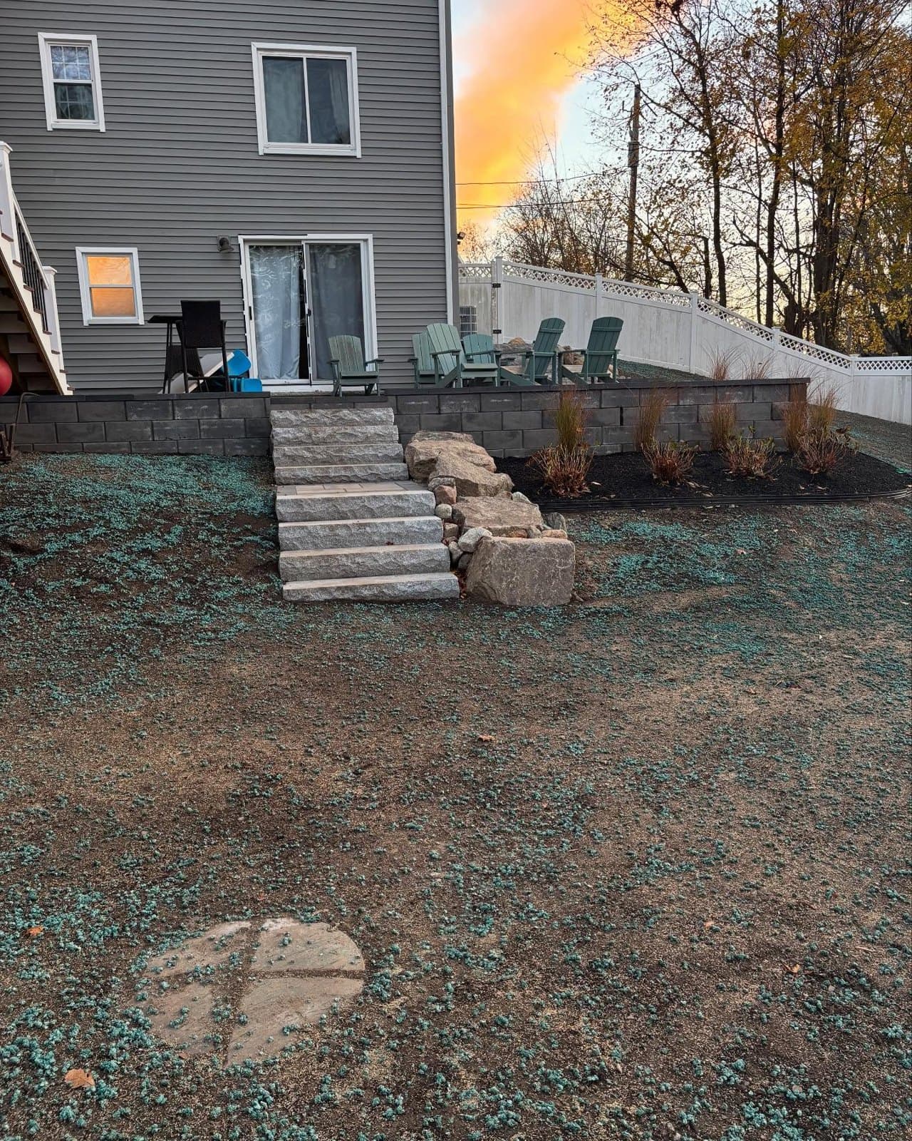 Granite steps set into a boulder retaining wall on a sloped yard
