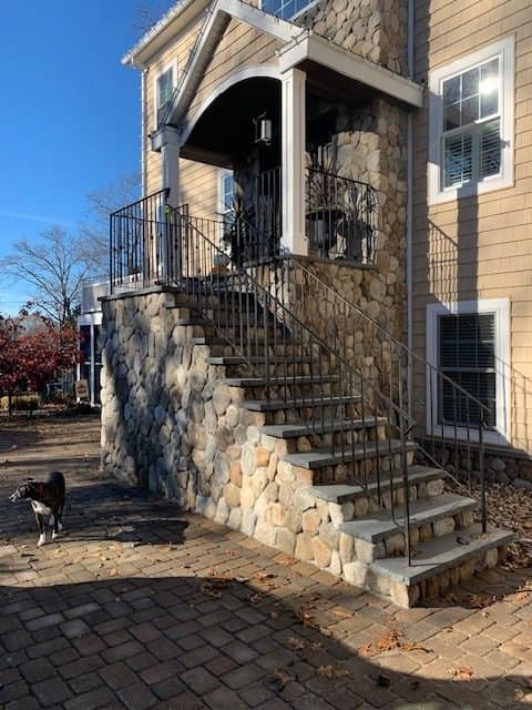 Fieldstone stairs with a black railing up to a side door