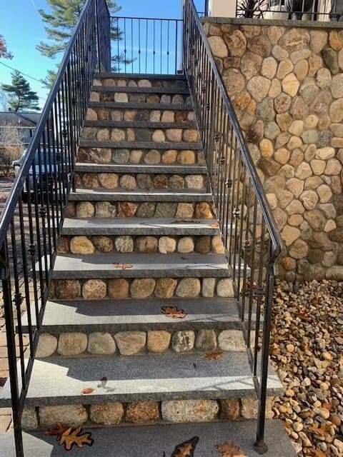 Stone steps with iron railing beside a fieldstone wall